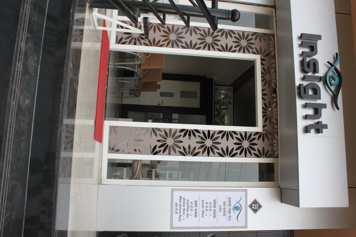 Insight Institute glazed entry portal with laser-cut floral side panels and a bilingual department directory plaque mounted on the façade